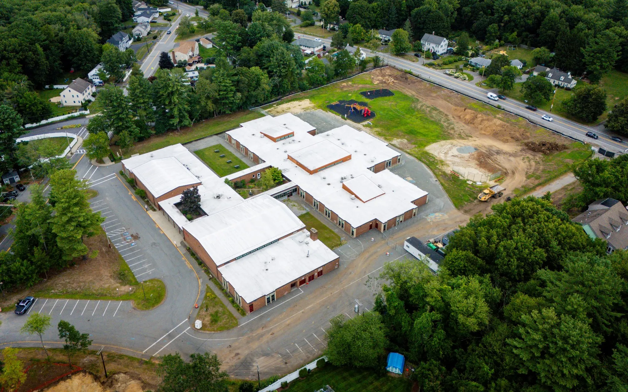 Drone photograph of the existing J.W. Killam Elementary School, built 1969 — single-story building with white roof surrounded by fall trees